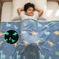 Child lying on a bed with a dinosaur-patterned blanket, including a close-up of glowing dinosaurs.
