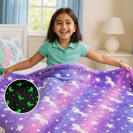 A child holding a purple blanket adorned with glowing unicorn and dragon patterns, featuring an inset that highlights the glow-in-the-dark effect.
