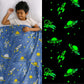 Child sleeping under a blue space-themed blanket with green glow-in-the-dark patterns.