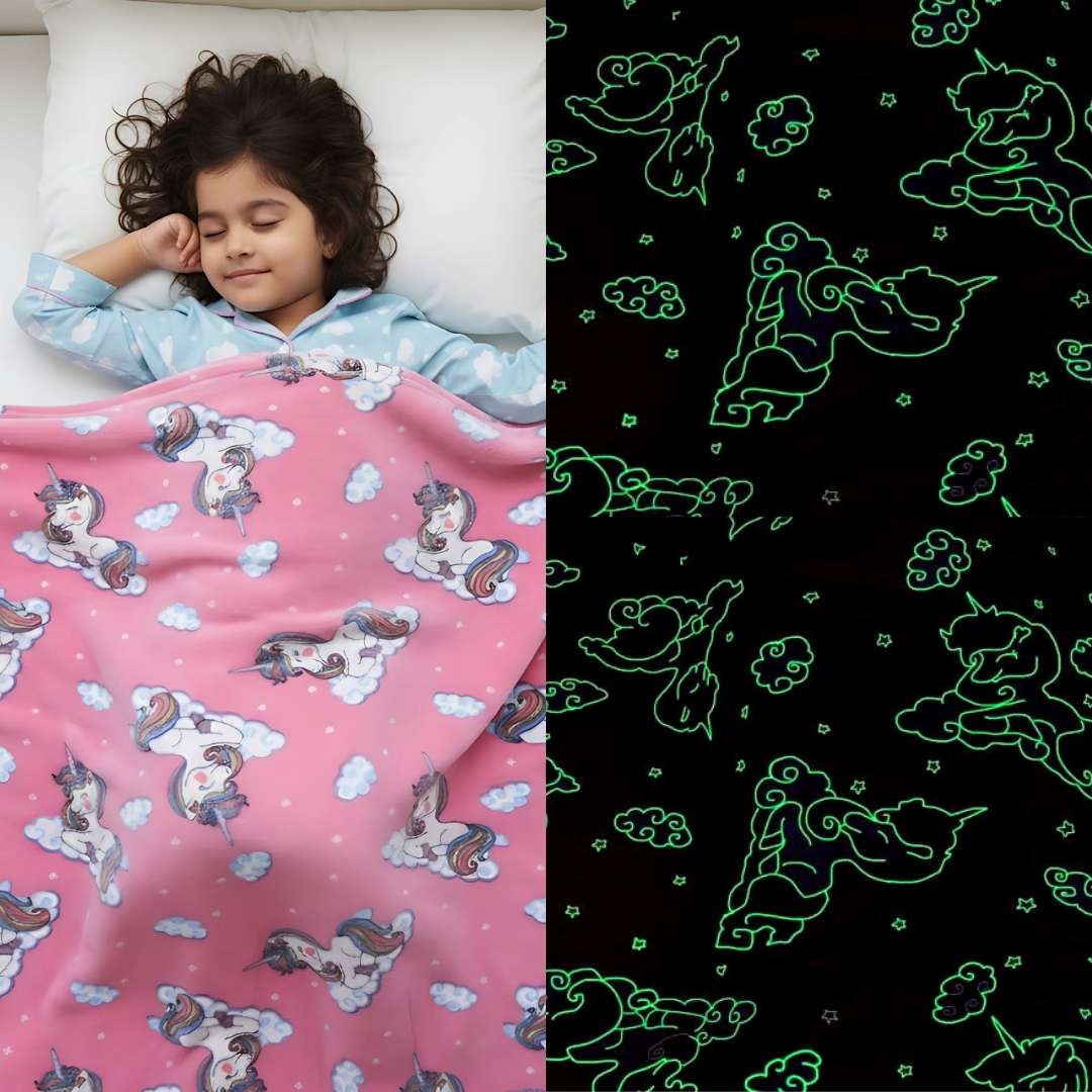Girl sleeping under a pink Famyo glow-in-the-dark blanket with unicorn and cloud patterns, glowing green in the dark.