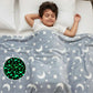 Child sleeping under a blanket with moon and star patterns, including a close-up of the glowing design.