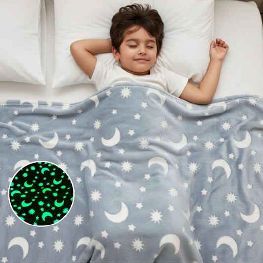 Child sleeping under a blanket with moon and star patterns, including a close-up of the glowing design.