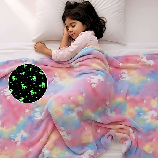 Child sleeping under a colorful blanket with a close-up of a glowing unicorn design.
