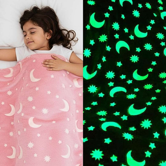 Girl sleeping under a pink Famyo glow-in-the-dark blanket with moon and star patterns, shown glowing green in the dark.