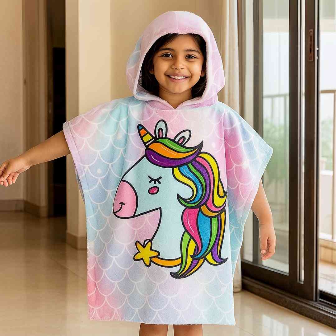 Child wearing Famyo Cute Pink & Blue Unicorn poncho towel for kids, ages 1–7 years. Quick-drying microfiber hooded bath towel with colorful unicorn design, perfect for bath, beach, or pool.