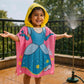 Smiling child wearing Famyo Magical Princess hooded poncho towel for kids, ages 1–7. Soft, quick-drying microfiber towel ideal for bath, beach, and pool.